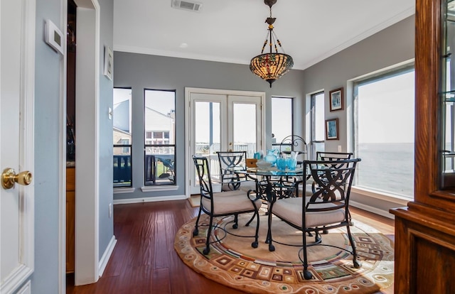 dining room featuring ornamental molding, a water view, dark hardwood / wood-style floors, and french doors