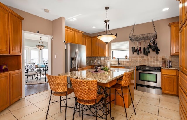 kitchen featuring a kitchen bar, light wood-type flooring, a center island, stainless steel appliances, and light stone counters