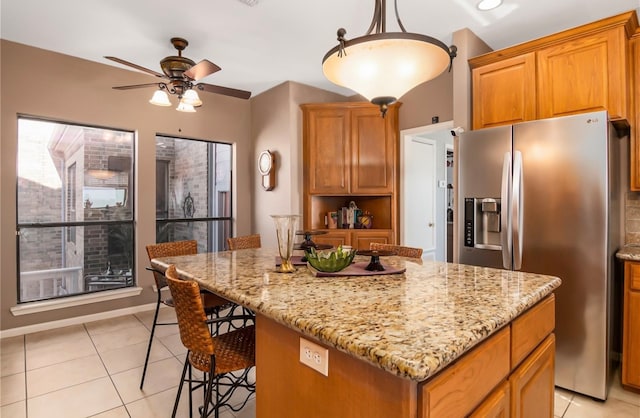 kitchen featuring stainless steel fridge, light tile patterned floors, hanging light fixtures, and a kitchen island