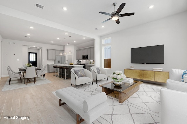 living room with ceiling fan, light hardwood / wood-style flooring, and sink