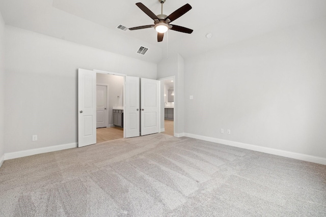 unfurnished bedroom featuring light colored carpet, high vaulted ceiling, ceiling fan, and ensuite bathroom