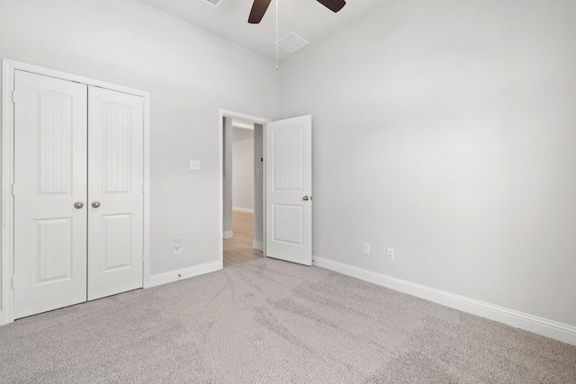 unfurnished bedroom with ceiling fan, light carpet, high vaulted ceiling, and a closet