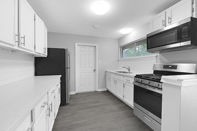 kitchen featuring tasteful backsplash, appliances with stainless steel finishes, sink, white cabinetry, and dark hardwood / wood-style floors