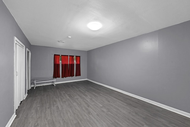 spare room featuring a textured ceiling and dark hardwood / wood-style flooring