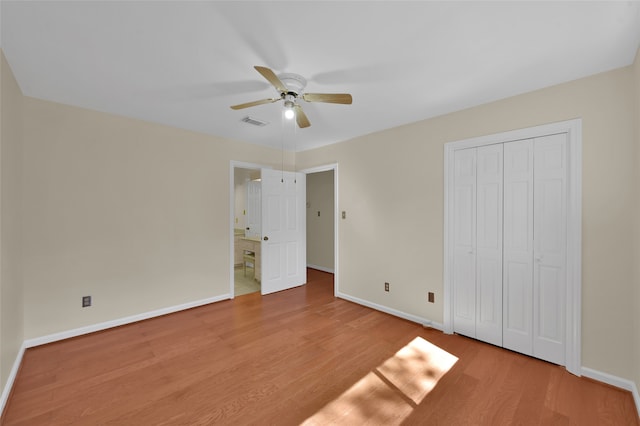 unfurnished bedroom featuring light hardwood / wood-style floors, a closet, connected bathroom, and ceiling fan