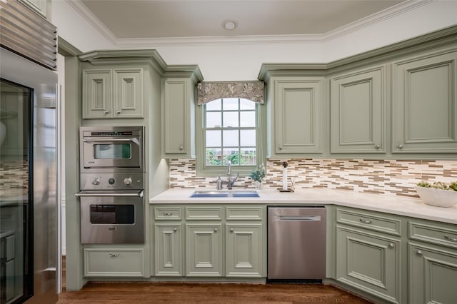 kitchen featuring green cabinets, appliances with stainless steel finishes, decorative backsplash, and sink