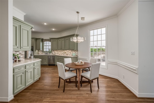 dining room with sink, an inviting chandelier, crown molding, and dark wood-type flooring