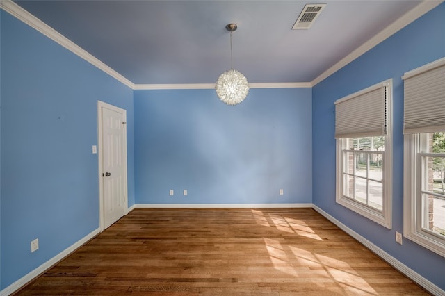 empty room with hardwood / wood-style floors, an inviting chandelier, and crown molding