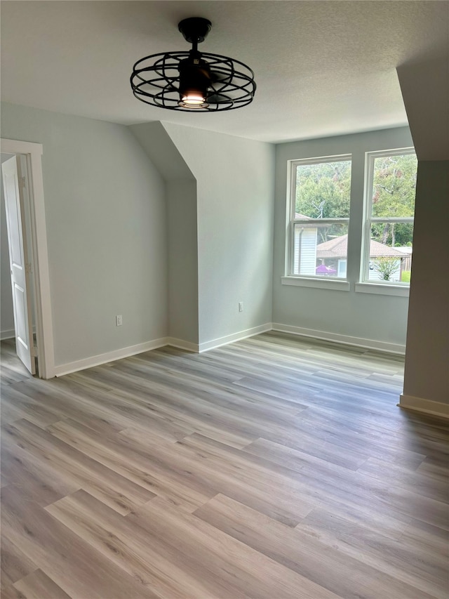 unfurnished dining area with a textured ceiling, light wood-type flooring, and ceiling fan