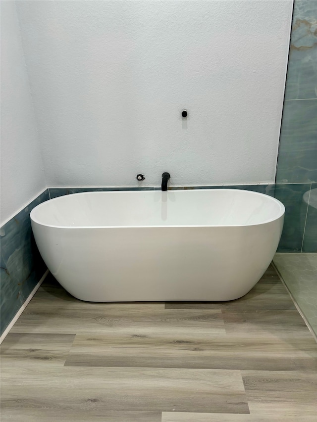 bathroom with hardwood / wood-style flooring and a bathtub