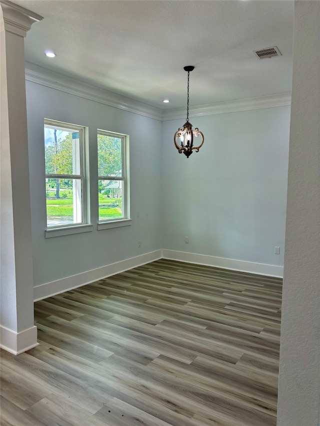 empty room with crown molding, hardwood / wood-style flooring, and a chandelier