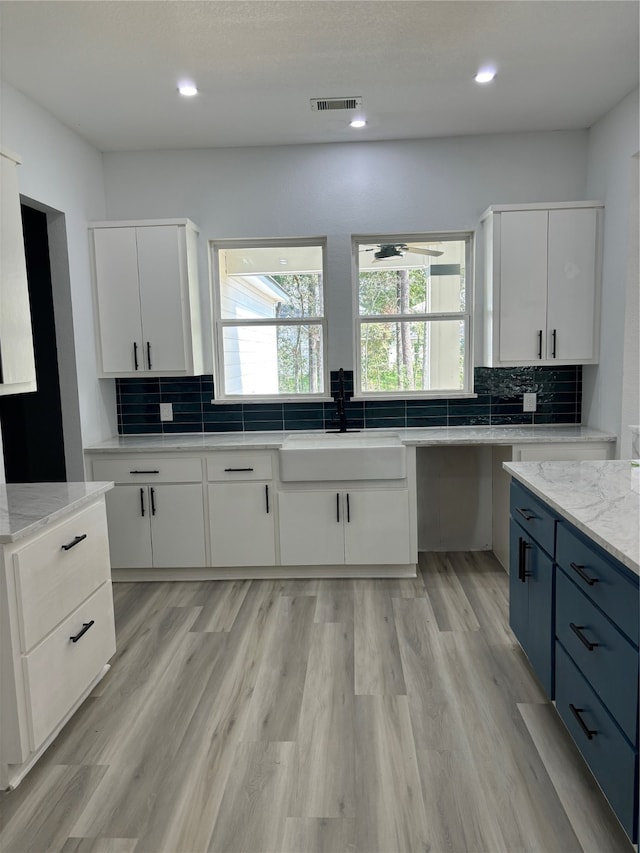 kitchen featuring light hardwood / wood-style flooring, white cabinets, blue cabinets, and sink