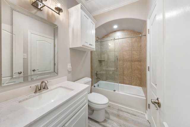 full bathroom with combined bath / shower with glass door, vanity, crown molding, hardwood / wood-style flooring, and toilet