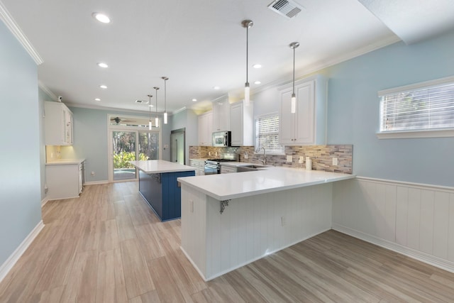 kitchen with a breakfast bar, white cabinets, hanging light fixtures, light wood-type flooring, and appliances with stainless steel finishes