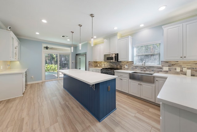 kitchen with pendant lighting, white cabinets, sink, appliances with stainless steel finishes, and a kitchen island