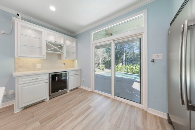 kitchen featuring stainless steel refrigerator, white cabinetry, wine cooler, light hardwood / wood-style flooring, and backsplash