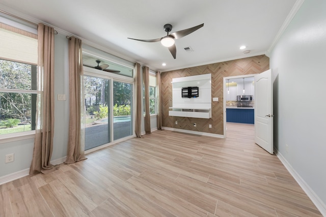 unfurnished living room featuring light hardwood / wood-style flooring, ceiling fan, ornamental molding, and wood walls