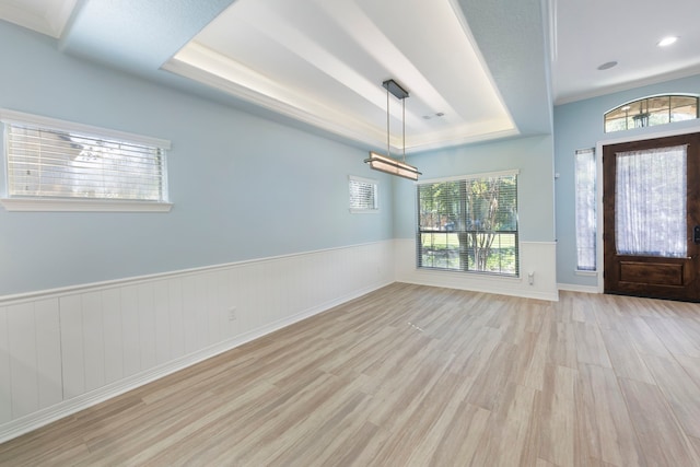 entryway featuring a tray ceiling, light hardwood / wood-style flooring, and a wealth of natural light