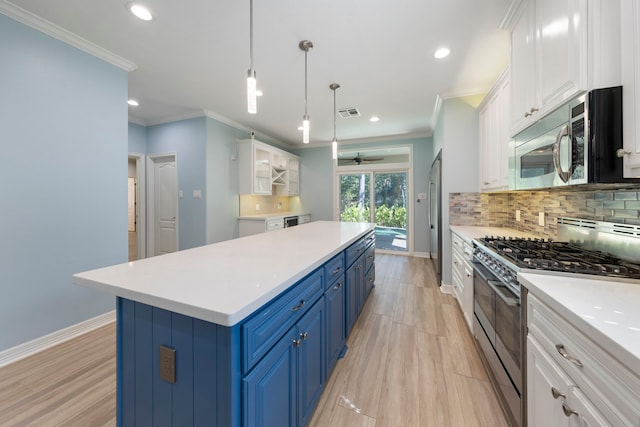 kitchen with blue cabinetry, appliances with stainless steel finishes, tasteful backsplash, decorative light fixtures, and white cabinetry