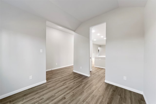 spare room featuring hardwood / wood-style flooring and vaulted ceiling