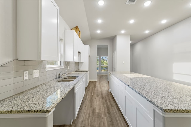 kitchen featuring light stone countertops, sink, light wood-type flooring, a kitchen island, and white cabinets