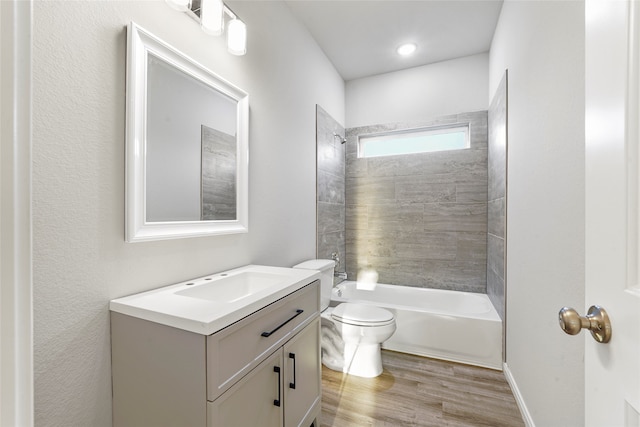 full bathroom featuring toilet, tiled shower / bath, hardwood / wood-style floors, and vanity