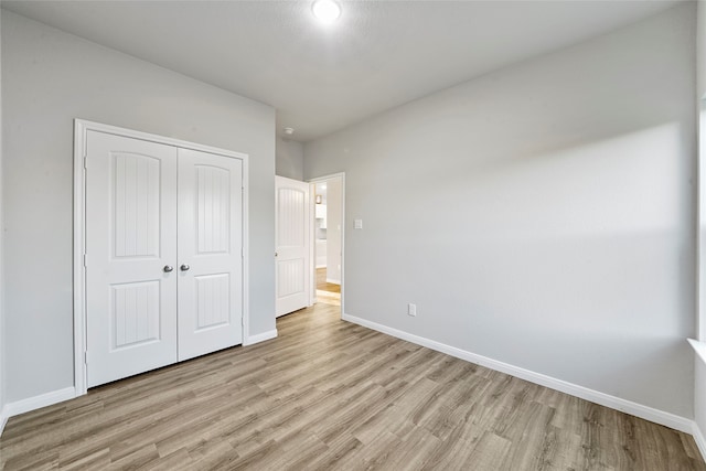 unfurnished bedroom with light wood-type flooring and a closet