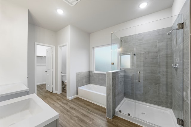 full bathroom featuring toilet, hardwood / wood-style floors, independent shower and bath, and vanity