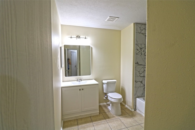 full bathroom featuring a textured ceiling, toilet, tiled shower / bath, vanity, and tile patterned flooring