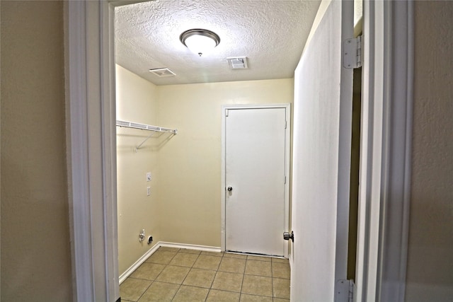 laundry room with a textured ceiling and light tile patterned floors