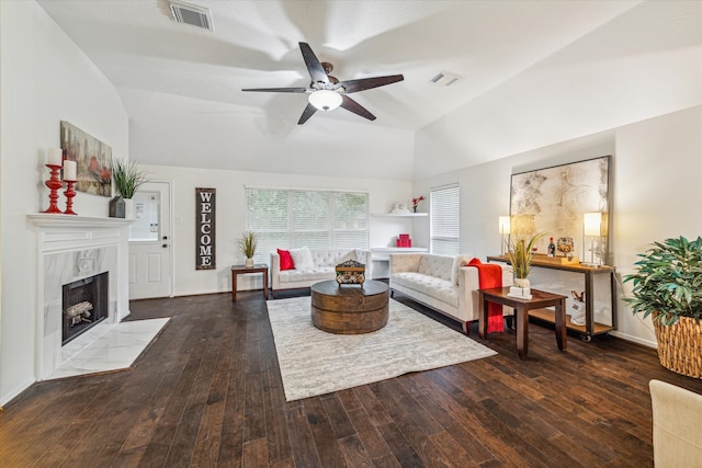 living room featuring dark wood-type flooring, ceiling fan, vaulted ceiling, and a fireplace