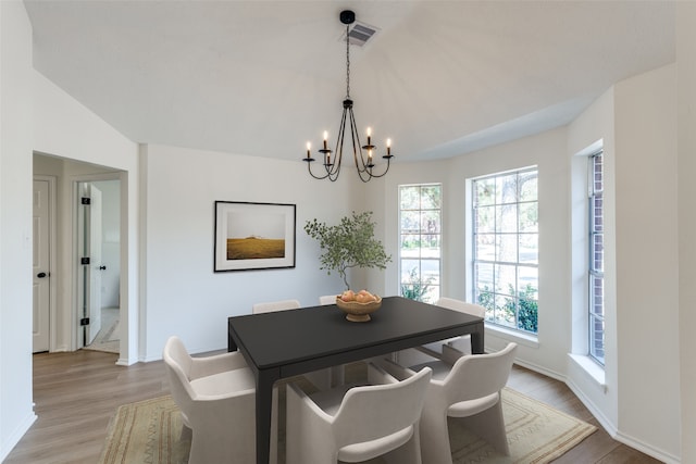 dining space with lofted ceiling, a notable chandelier, and light hardwood / wood-style floors