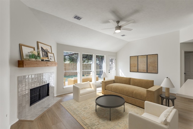 living room with vaulted ceiling, light hardwood / wood-style flooring, a fireplace, and ceiling fan