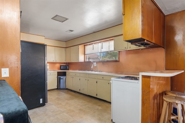 kitchen with a breakfast bar area, sink, black appliances, and kitchen peninsula