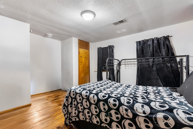 bedroom with a textured ceiling and light wood-type flooring