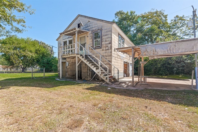 rear view of house featuring a patio, a carport, and a lawn