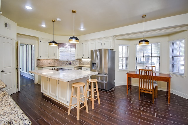 kitchen with appliances with stainless steel finishes, white cabinetry, decorative light fixtures, and dark hardwood / wood-style flooring