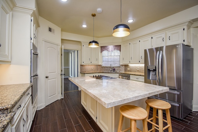 kitchen with sink, a center island, pendant lighting, appliances with stainless steel finishes, and dark hardwood / wood-style flooring