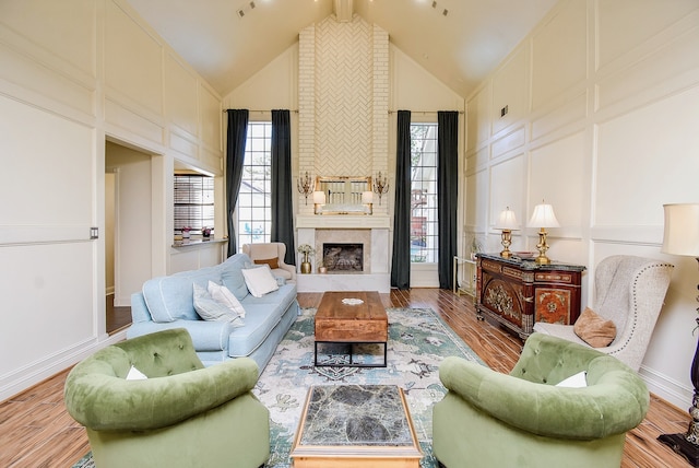 living room with a large fireplace, high vaulted ceiling, and light wood-type flooring