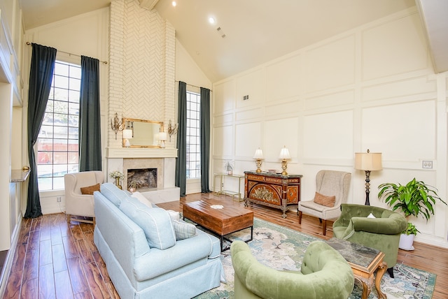 living room with hardwood / wood-style flooring, high vaulted ceiling, a large fireplace, and a wealth of natural light