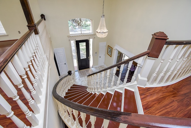 foyer entrance featuring hardwood / wood-style floors, a notable chandelier, and a towering ceiling