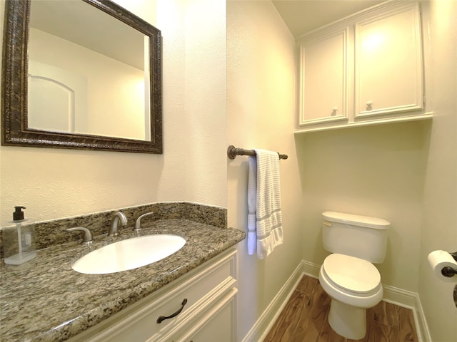 bathroom with vanity, toilet, and hardwood / wood-style flooring