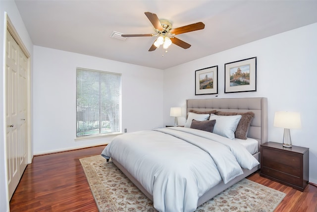 bedroom with a closet, dark hardwood / wood-style floors, and ceiling fan