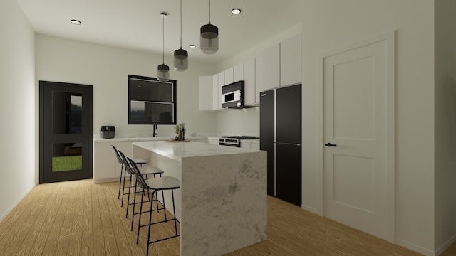 kitchen featuring a kitchen island, white cabinetry, light hardwood / wood-style flooring, black appliances, and pendant lighting