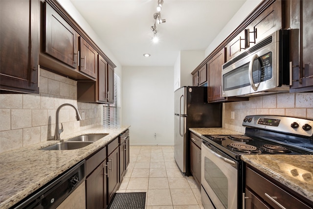 kitchen featuring appliances with stainless steel finishes, light tile patterned flooring, sink, dark brown cabinetry, and light stone counters