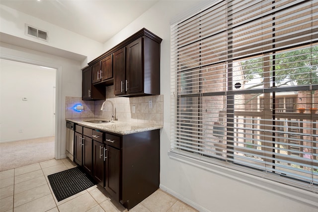 kitchen with backsplash, light tile patterned floors, light stone countertops, dark brown cabinetry, and sink