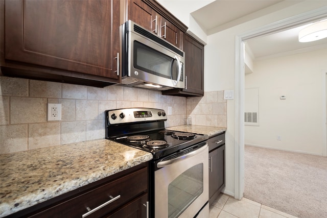 kitchen featuring light stone counters, backsplash, stainless steel appliances, dark brown cabinetry, and light colored carpet