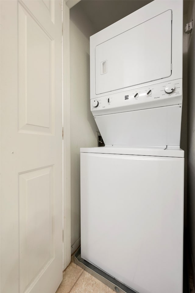 laundry area with stacked washer / drying machine and light tile patterned flooring