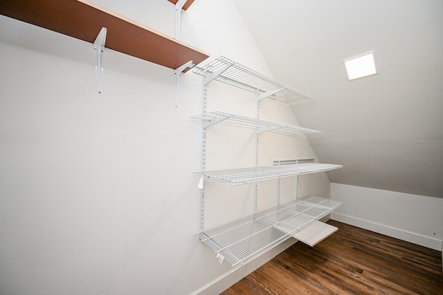 walk in closet with vaulted ceiling and dark hardwood / wood-style floors