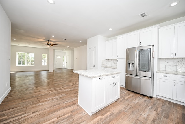 kitchen featuring stainless steel fridge, white cabinets, decorative backsplash, and light hardwood / wood-style floors